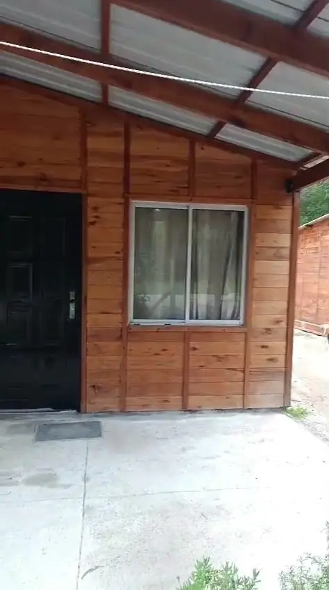Frente de una vivienda de madera terminada, con galería y puerta de entrada