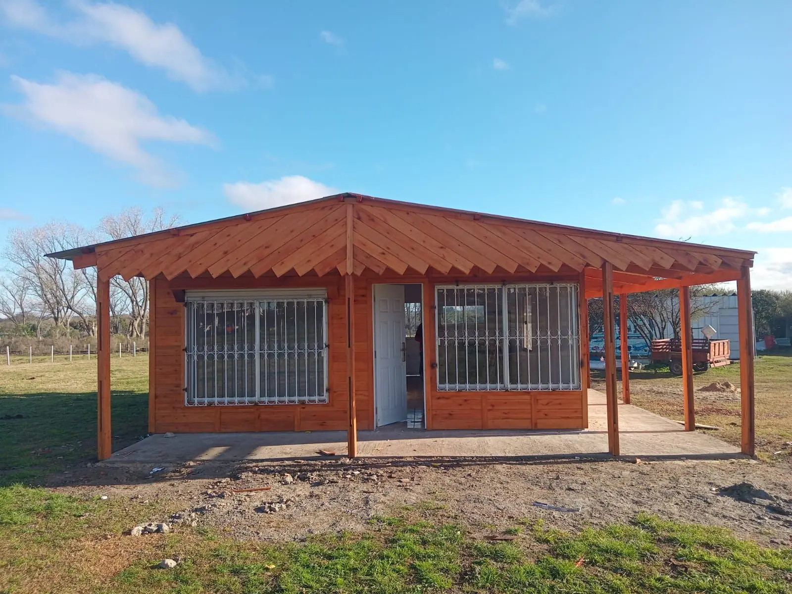 Vivienda de madera terminada con galería al frente y rejas en las ventanas