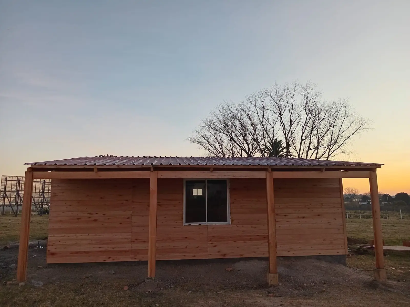 Vivienda con el techo de chapa colocado y la galería al frente, al atardecer