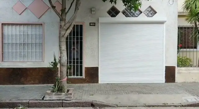 Cortina de enrollar blanca cerrando el garaje de una casa