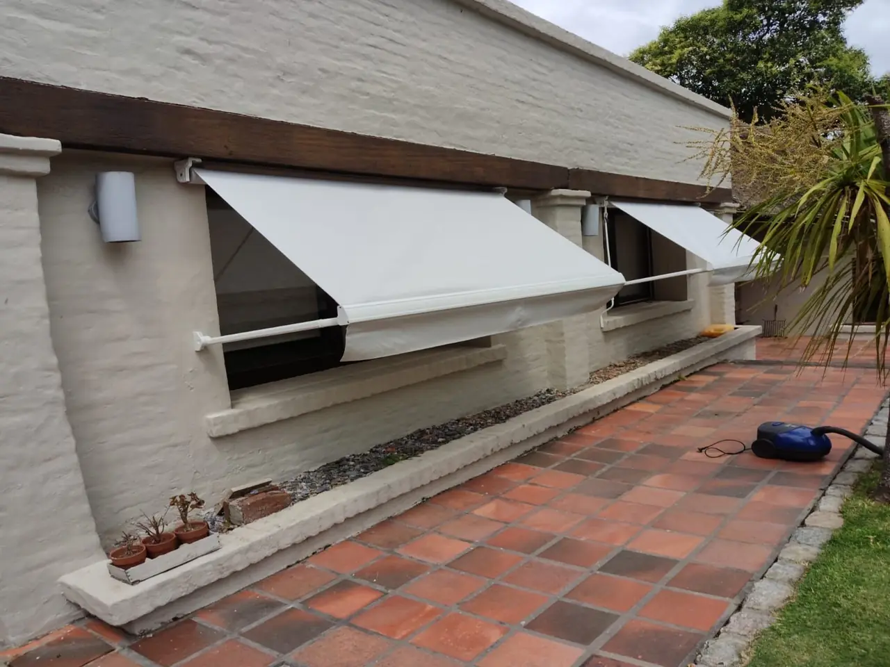 Toldo de brazo invisible blanco en una fachada de ladrillo