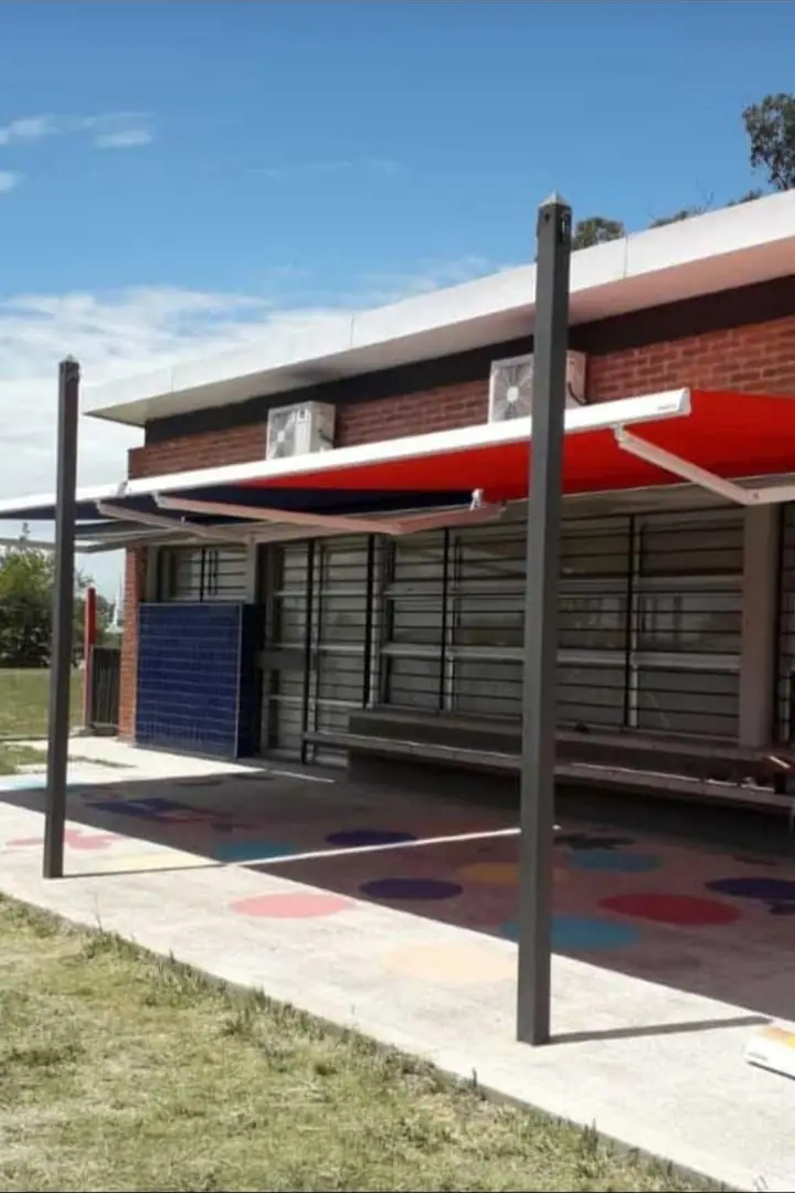 Toldo de brazo invisible rojo sobre la vereda de un comercio