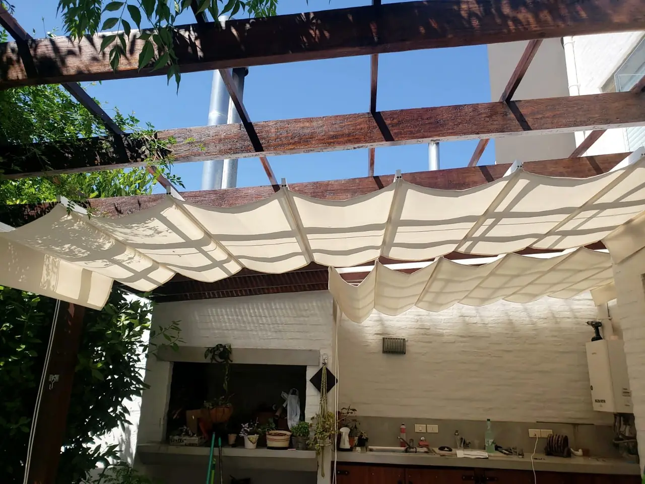 Toldo corredizo de lona clara bajo la estructura de un patio