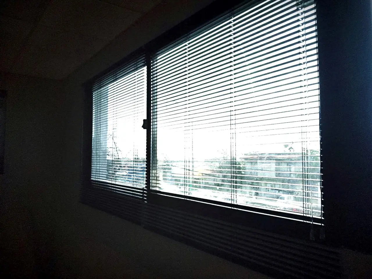 Veneciana de aluminio negra en una ventana corrediza